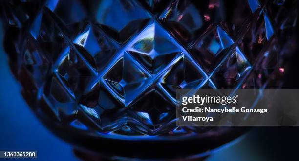 close up of a the  decorative cut crystal  on a blue wine glass - kristallglas stock-fotos und bilder