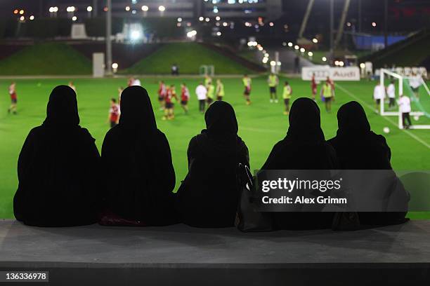 Women in traditional clothes watch a training session of Bayern Muenchen at the ASPIRE Academy for Sports Excellence on January 2, 2012 in Doha,...