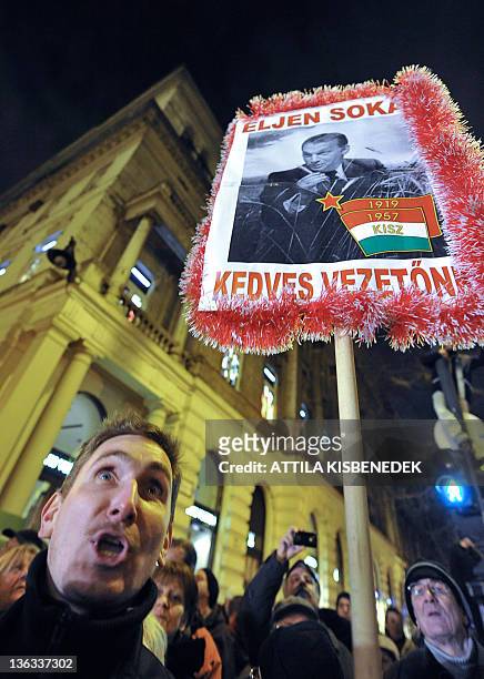 Man shouts anti-government slogans beside a photo of Hungarian Prime Minister Viktor Orban with the tricolor of the former Communist Youth Alliance...