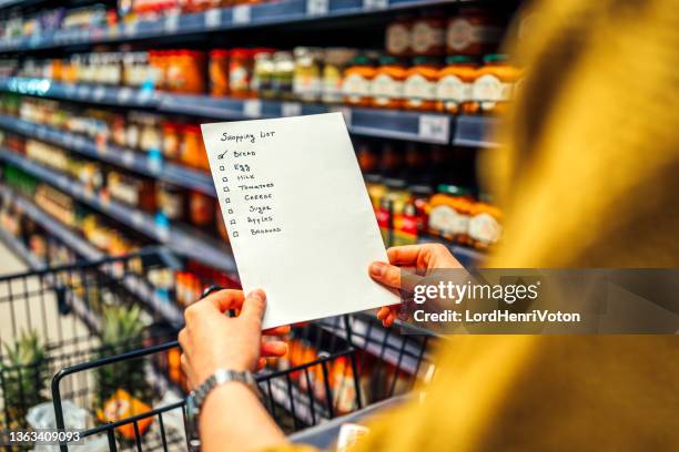 frau mit einkaufsliste im lebensmittelgeschäft - einkaufszettel stock-fotos und bilder