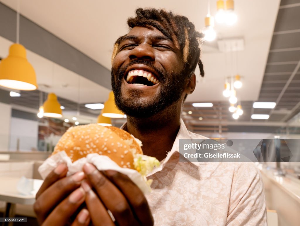 Young man enjoying having burger at a restaurant