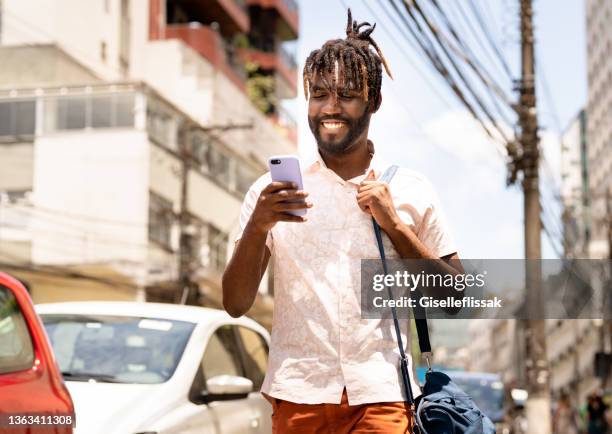 jovem elegante usando seu telefone enquanto caminhava pela rua - brazilian men - fotografias e filmes do acervo