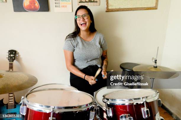 glückliche schlagzeugerin genießt es, in ihrem studio schlagzeug zu spielen - drums stock-fotos und bilder