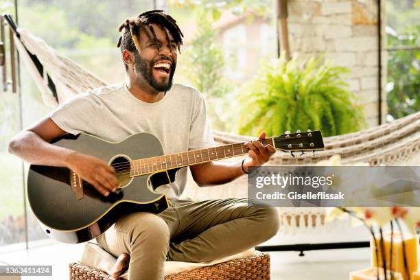 smiling young man playing an acoustic guitar - gitaar stock pictures, royalty-free photos & images