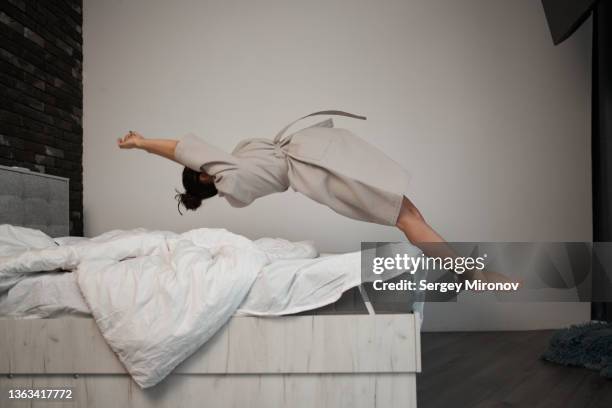 unrecognizable woman falling on bed - woman mid air stock pictures, royalty-free photos & images