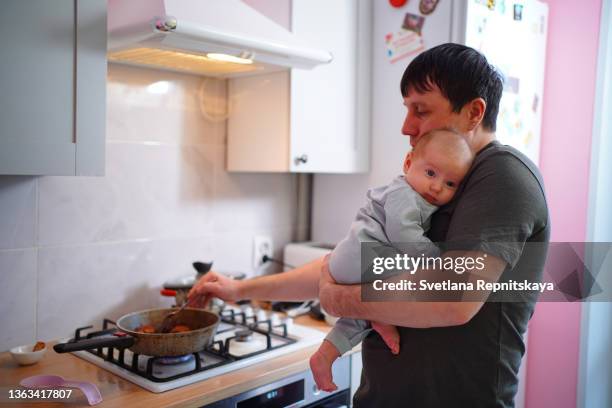 father in the kitchen with a baby in his arms - gasspis bildbanksfoton och bilder