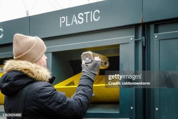 man recycelt plastikflaschen an den wertstoffbehältern - hineinstecken stock-fotos und bilder