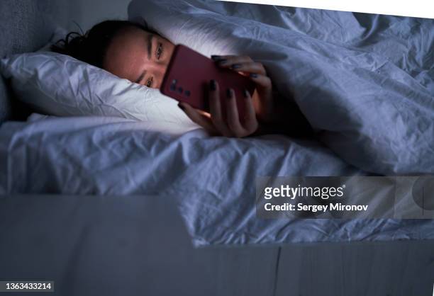 lady messaging on smartphone in bed - getting out of bed stock-fotos und bilder