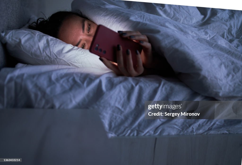 Lady messaging on smartphone in bed