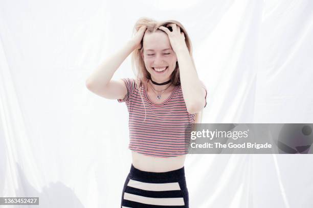 smiling young woman with hands in hair against white background - crop top stock pictures, royalty-free photos & images