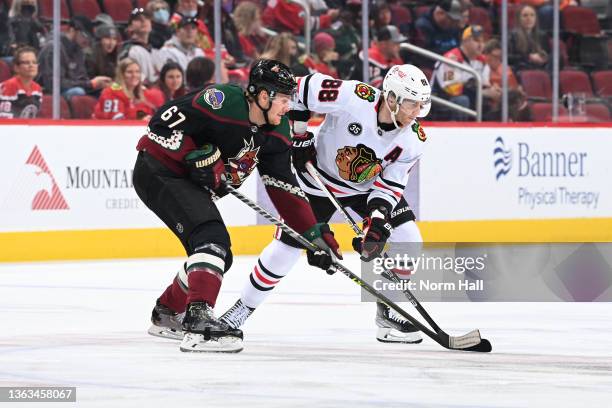 Lawson Crouse of the Arizona Coyotes and Patrick Kane of the Chicago Blackhawks get ready during a face off at Gila River Arena on January 06, 2022...