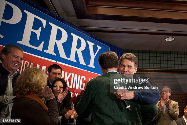 Texas Governor and Republican presidential candidate Rick Perry gives a hug to Kansas Governor Sam Brownback at the Hotel Pattee on January 2, 2012...