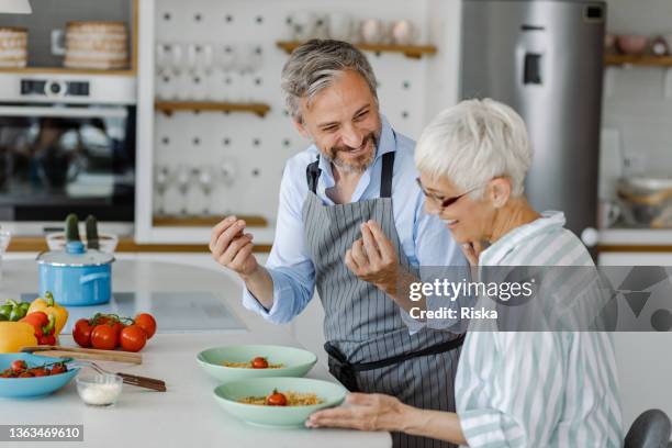 彼の妻のために夕食を準備する成熟した男 - middle aged couple cooking ストックフォトと画像