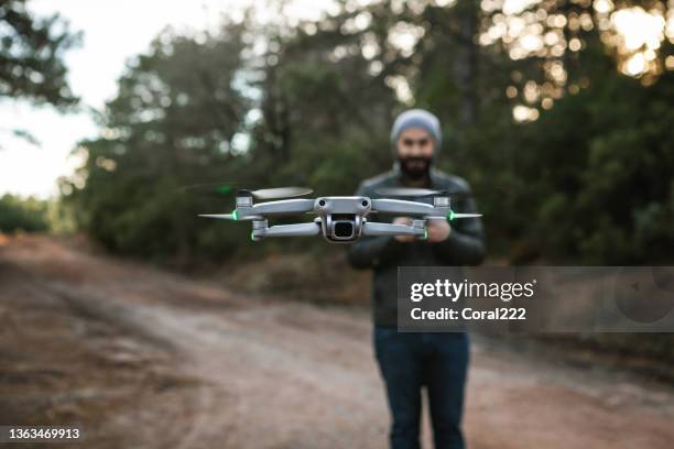 el piloto masculino está volando un dron con control remoto - remote controlled fotografías e imágenes de stock