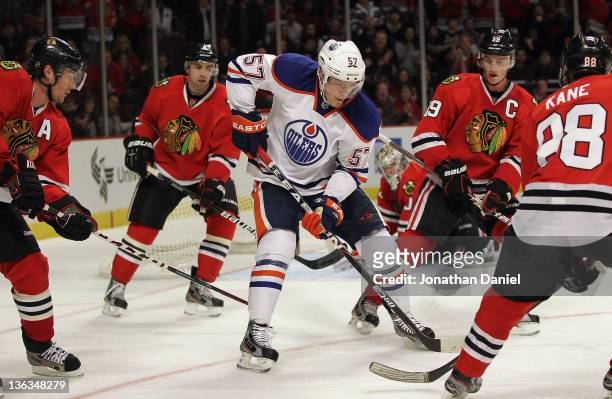 Anton Lander of the Edmonton Oilers controls the puck surrounded by Duncan Keith, Nick Leddy, Jonathan Toews and Patrick Kane of the Chicago...