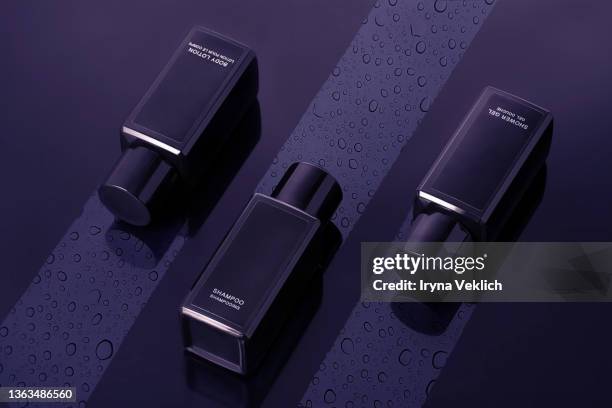 beauty products moisturizing  shower gel, shampoo and body lotion with drops of water on a dark black background. trendy color of the year 2022 very peri purple violet lavender. - bubble bath bottle stock pictures, royalty-free photos & images