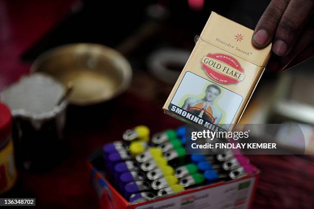 An Indian street vendor poses with a packet of cigarettes, adorned with an image said to resemble that of Chelsea and England footballer John Terry,...