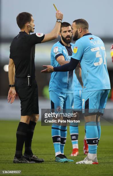Referee Declan Bourne shows a yellow card to Joel Lynch of Crawley Town during the Sky Bet League Two match between Northampton Town and Crawley Town...