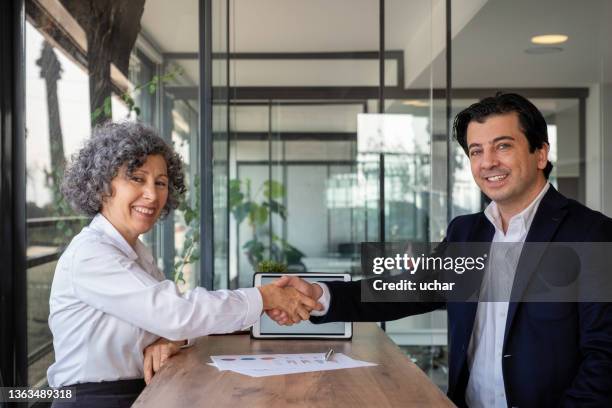 lächelnde senior-geschäftsfrau handschlagpartnerin nach erfolgreicher verhandlung - handshaking in a bank stock-fotos und bilder