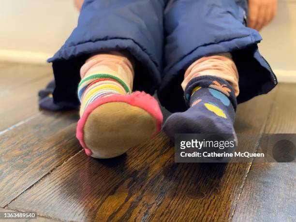 young mixed-race girl wearing snow pants sits on steps preparing to go outside to play in snow - girl socks - fotografias e filmes do acervo