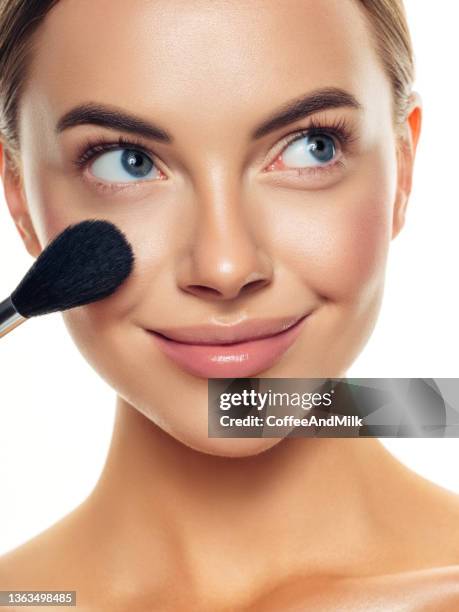 beautiful young woman applying foundation powder - make up blush imagens e fotografias de stock