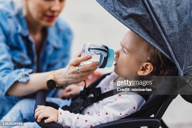 primer plano de una mujer anónima dándole agua a su hijo - adult baby bottle fotografías e imágenes de stock