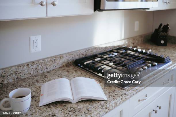 drink in mug next to cookbook on kitchen counter - cookbook stock pictures, royalty-free photos & images