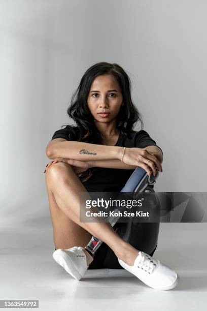 portrait of a strong female with a prosthetic leg crossed legged - amputee woman imagens e fotografias de stock
