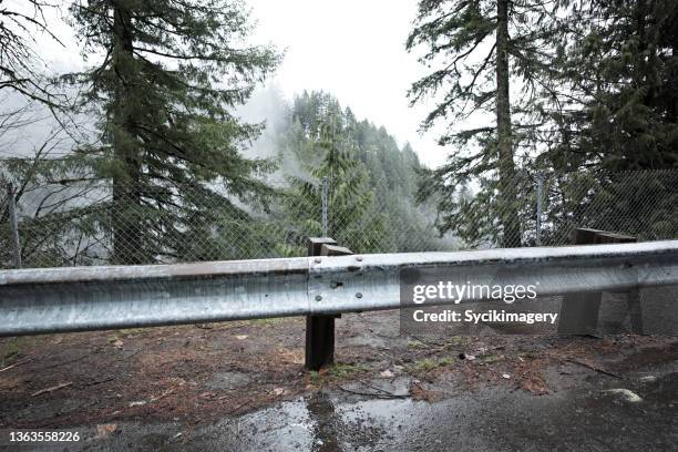 crash barrier along highway in foggy mountain landscape - crash barrier stock pictures, royalty-free photos & images