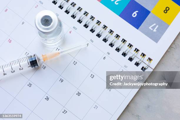 syringe and vaccine on a calendar - week schedule stock pictures, royalty-free photos & images