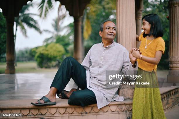 girl playing with her grandfather sitting in an architectural dome - indian grandparents stock pictures, royalty-free photos & images