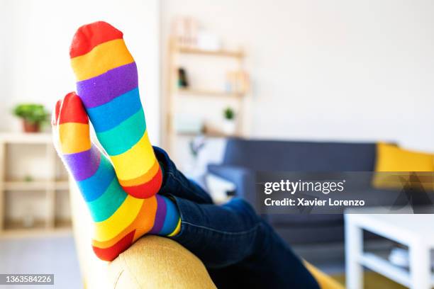 woman wearing colourful striped socks while relaxing on a sofa at home. - legs in stockings stockfoto's en -beelden