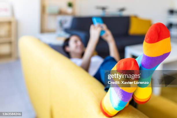 woman using a mobile phone while lying on a couch wearing colorful stockings. - strümpfe stock-fotos und bilder