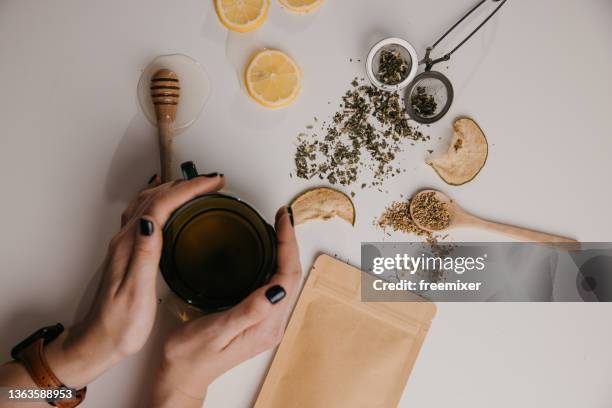 woman hands hold glass cup of tea on table with other tea props - tesil bildbanksfoton och bilder