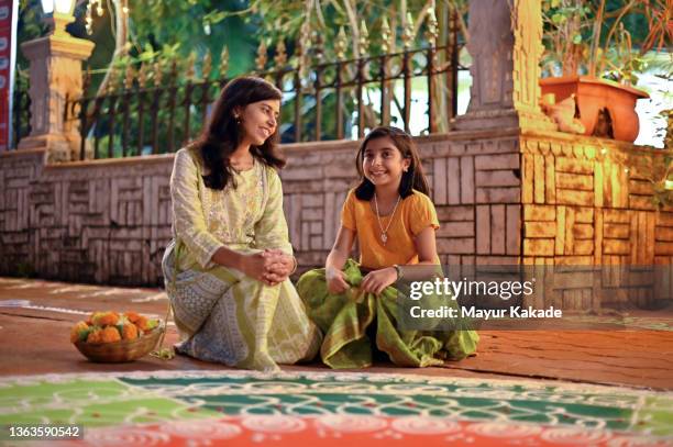 mother and daughter sitting together near a rangoli design - indian kolam stock-fotos und bilder