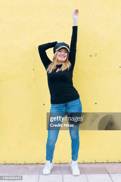 full body smiling blonde girl raising arms on colorful background outdoors - man standing full body stock-fotos und bilder