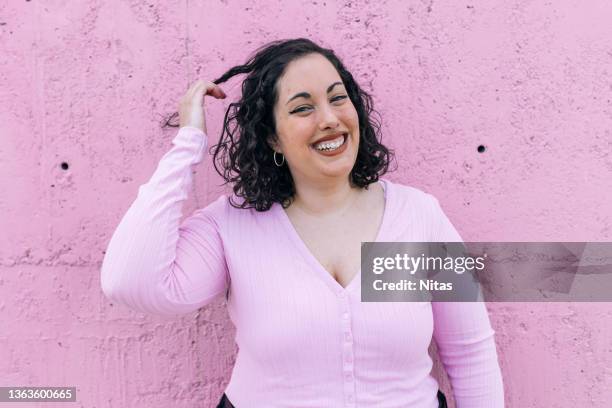 female touching her hair on pink background - buxom women ストックフォトと画像