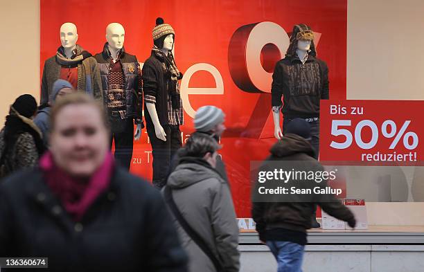 People walk past a clothing store advertising sales on January 3, 2012 in Berlin, Germany. Many German retailers are offering heavy discounts in the...
