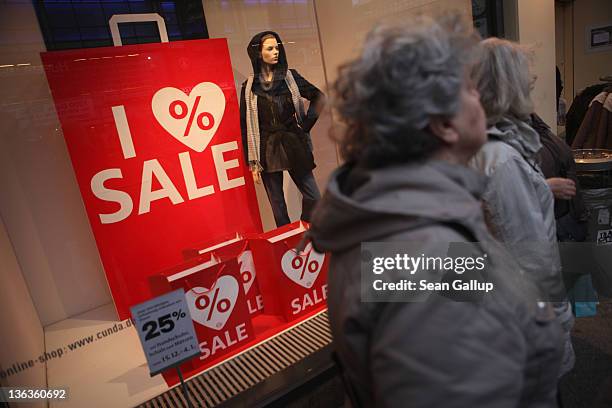 People stand next to a store advertising sales on January 3, 2012 in Berlin, Germany. Many German retailers are offering heavy discounts in the weeks...