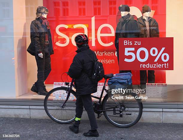 Woman with a bicycle looks at a display window of a store advertising sales on January 3, 2012 in Berlin, Germany. Many German retailers are offering...
