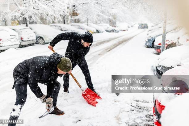 two friends are solving the problems with snow around car using shovels. - city of spades bildbanksfoton och bilder