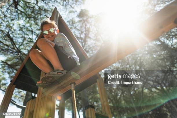 teenage boy climbing on a playground - speeltuintoestellen stockfoto's en -beelden