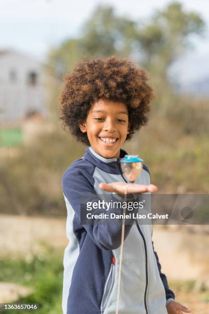 african american boy playing with his spinning top in the park. - peonza stockfoto's en -beelden