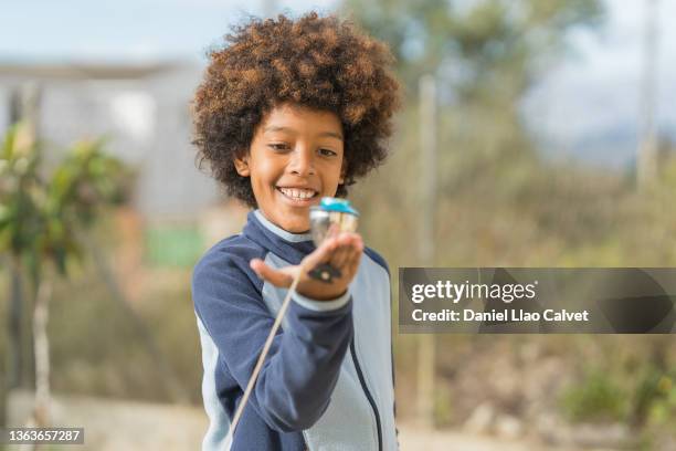 a boy outdoors playing with spinning top in holidays. - spinning top stock pictures, royalty-free photos & images