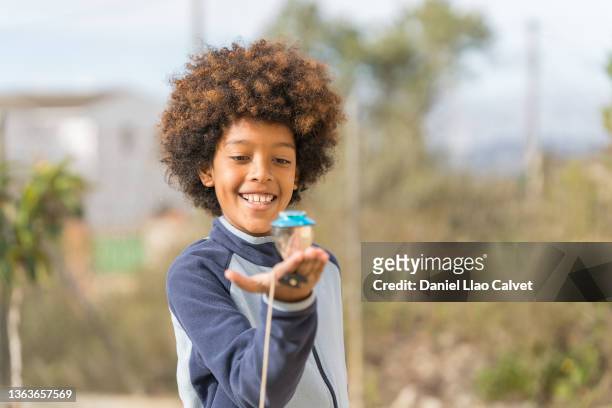african american boy playing with his spinning top in the park. - peonza stockfoto's en -beelden