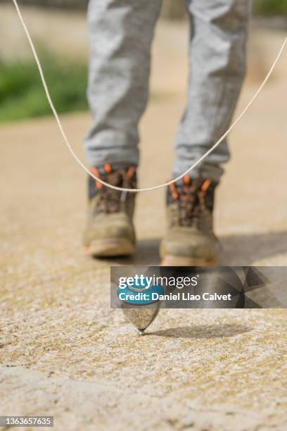 low section of boy spinning top on street - peonza imagens e fotografias de stock