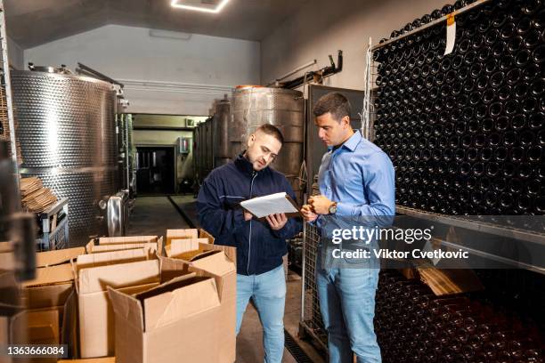 the owner of the winery and quality control expert checking the quality of wine in the wine cellar - examining wine stock pictures, royalty-free photos & images