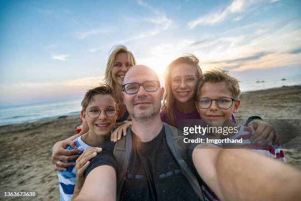 padres e hijos tomándose selfie en una playa por la noche - five people fotografías e imágenes de stock