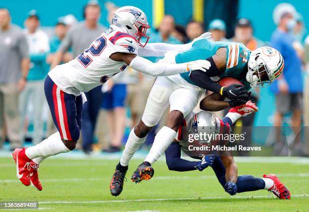 DeVante Parker of the Miami Dolphins is tackled on a carry by Devin McCourty and J.C. Jackson of the New England Patriots in the first quarter of the...