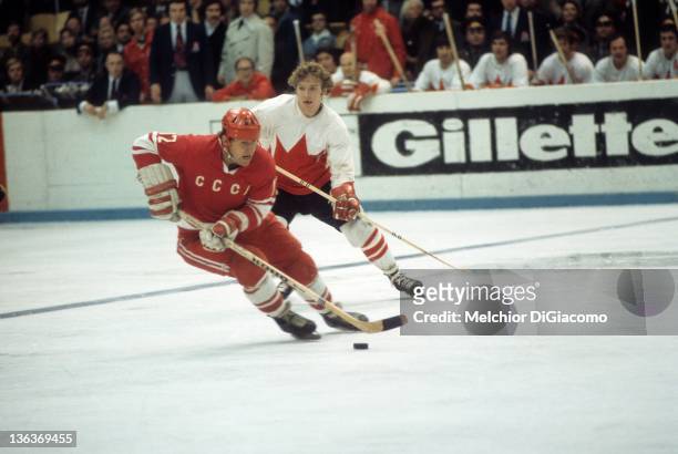 Yevgeny Mishakov of the Soviet Union skates with the puck as Bobby Clarke of Canada follows behind during the 1972 Summit Series at the Luzhniki Ice...